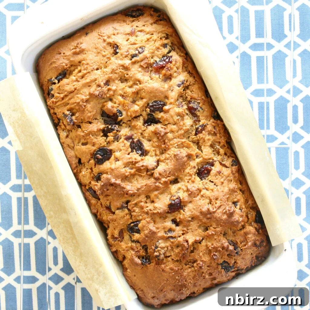 A beautifully baked loaf of vegan gluten-free Welsh fruit bread (Bara Brith) presented in a white dish against a serene blue and white background, ready to be sliced and enjoyed.