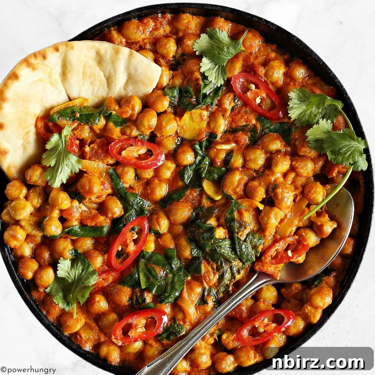 High-protein chickpea curry served with a piece of naan bread on the side.