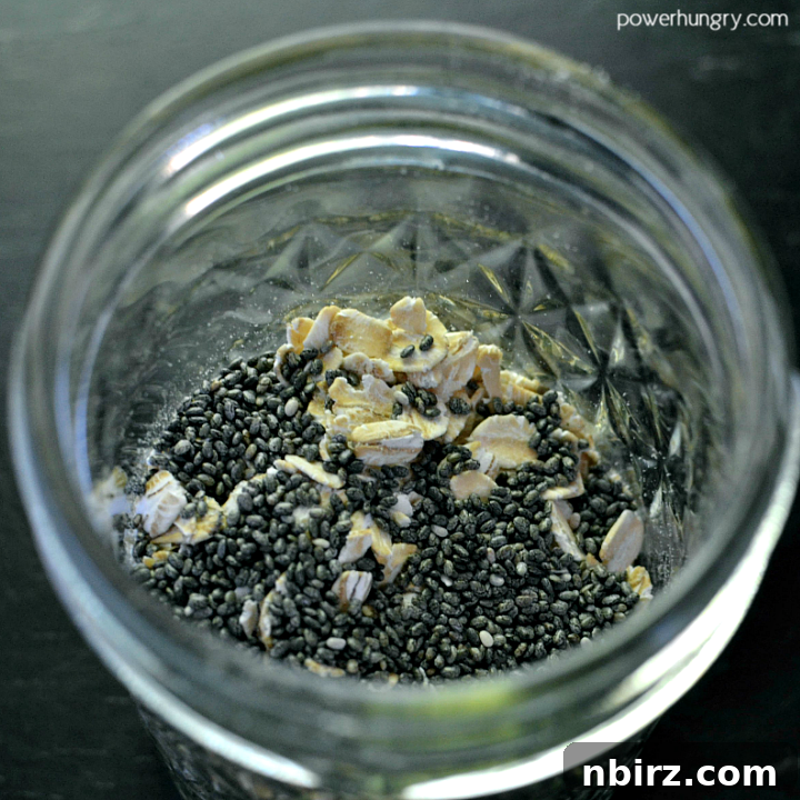 Rolled oats and chia seeds settling at the bottom of a glass jar, placed on a piece of slate