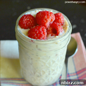A jar full of banana chia overnight oats, filled to the brim and topped with fresh raspberries