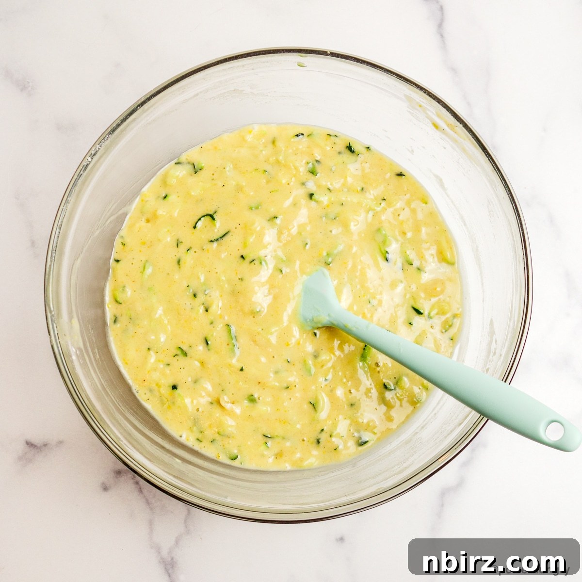 A glass bowl filled with the prepared 3-ingredient vegan zucchini muffin batter, ready for portioning.