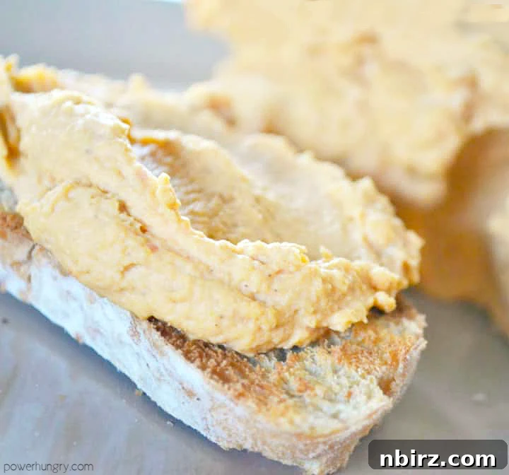Creamy Oil-Free Hummus Without Tahini 3 Thick, healthy oil-free hummus generously spread on a slice of toasted whole-grain bread, ready for a nutritious snack.