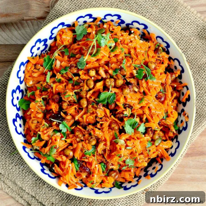 Moroccan Carrot Chickpea Salad in a blue and white bowl sitting atop a piece of burlap, garnished with fresh herbs