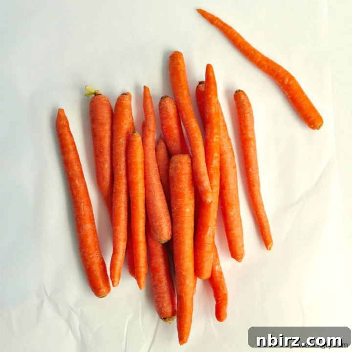 Overhead shot of fresh, vibrant carrots on a piece of white parchment paper, ready for preparation