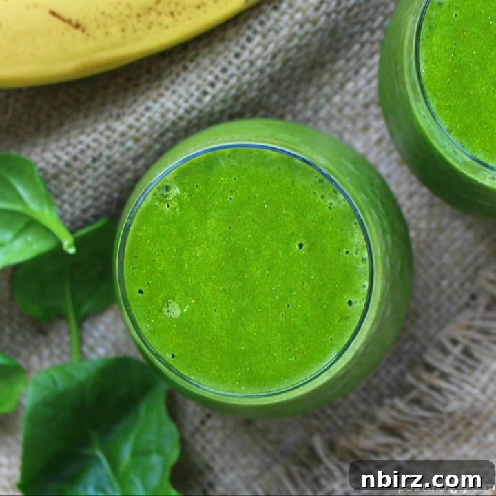 Revitalizing Green Energy Smoothie 3 Close-up of a refreshing green smoothie in a glass, elegantly placed on a piece of burlap, with a fresh banana and vibrant spinach leaves artistically arranged in the soft-focus background.