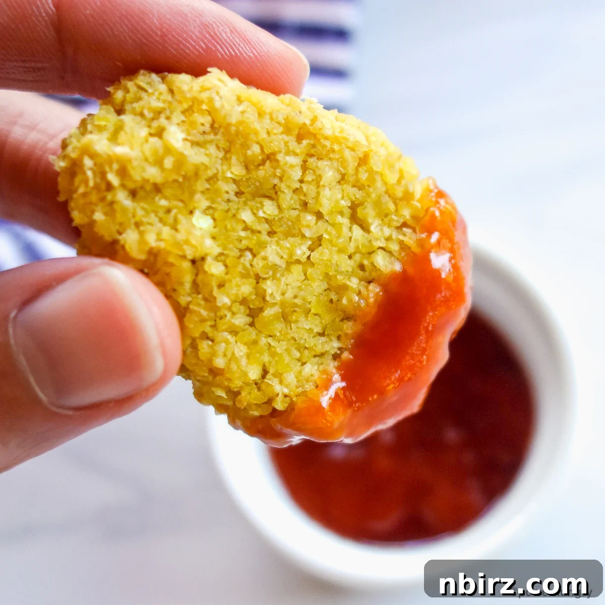 Protein-Packed Millet Nuggets: Just Two Ingredients 3 A single vegan millet nugget dipped into a bowl of red ketchup