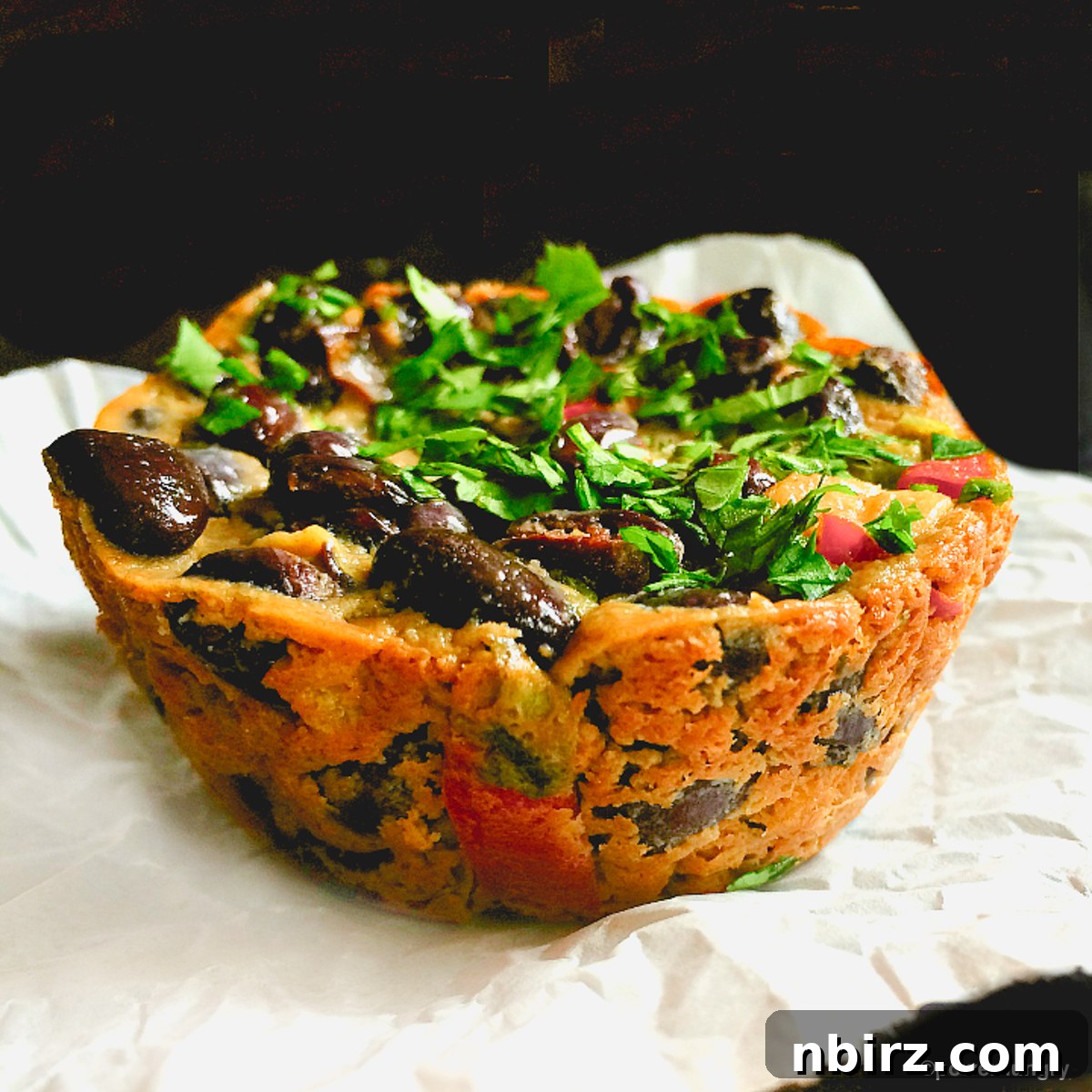 Tex-Mex Black Bean Plant Protein Frittatas 3 Four perfectly baked Tex-Mex black bean vegan frittatas neatly arranged on white paper, showcasing their appealing appearance and readiness to be enjoyed.