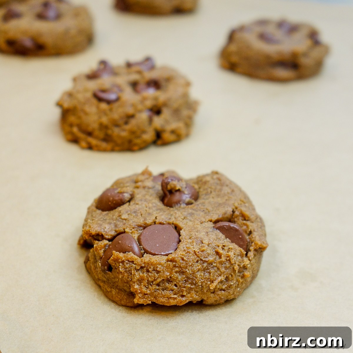Freshly baked chocolate chip flax cookies, golden brown at the edges, resting on a baking sheet straight from the oven.