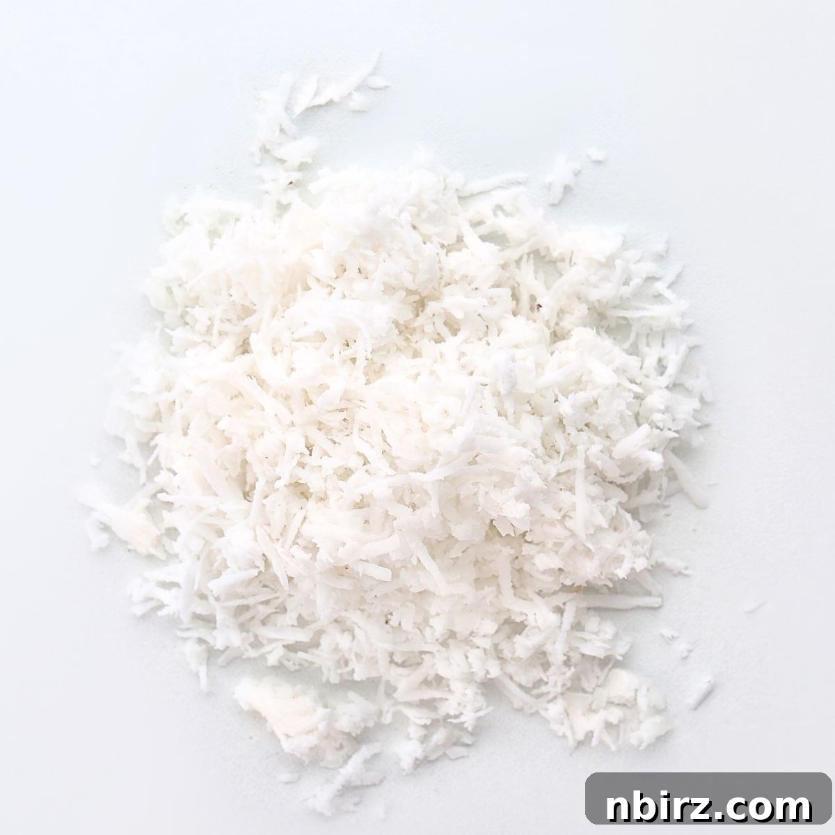 A generous pile of unsweetened coconut flakes, glistening and ready to be transformed into creamy, homemade coconut butter.