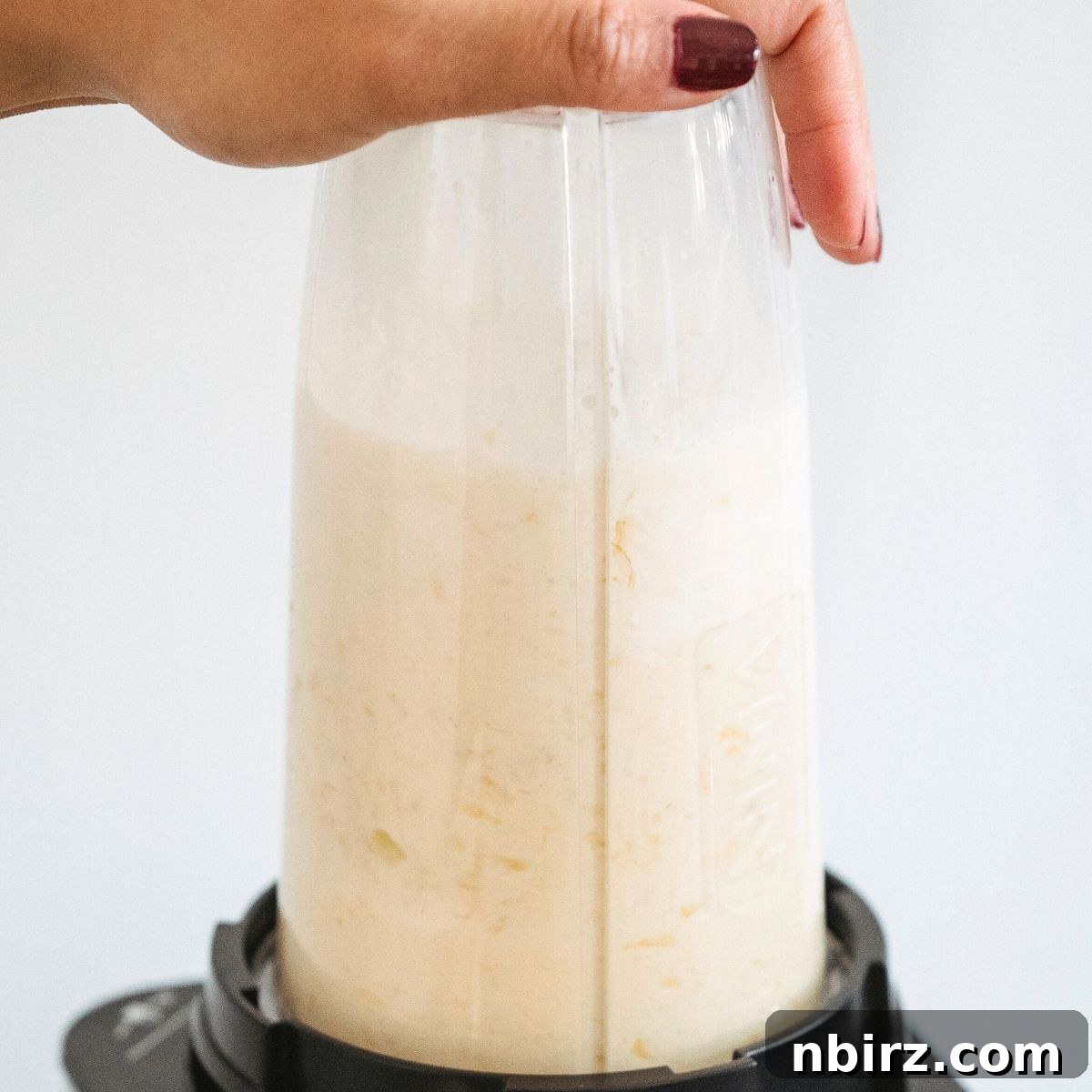 A high-speed bullet blender with coconut butter being processed, clearly showing its transition to a creamy, smooth state.