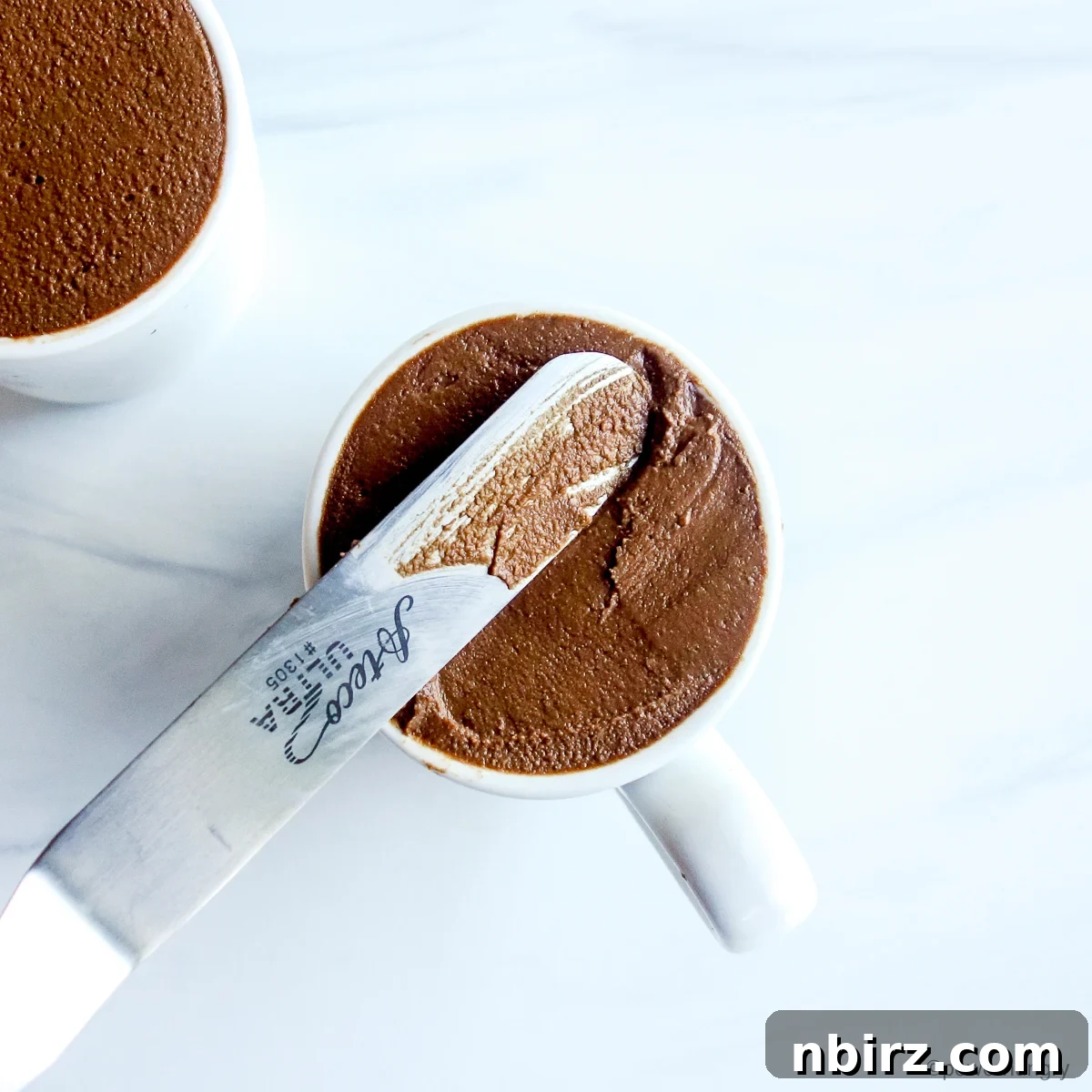 White espresso cups filled with leveled chocolate mousse, ready for chilling.