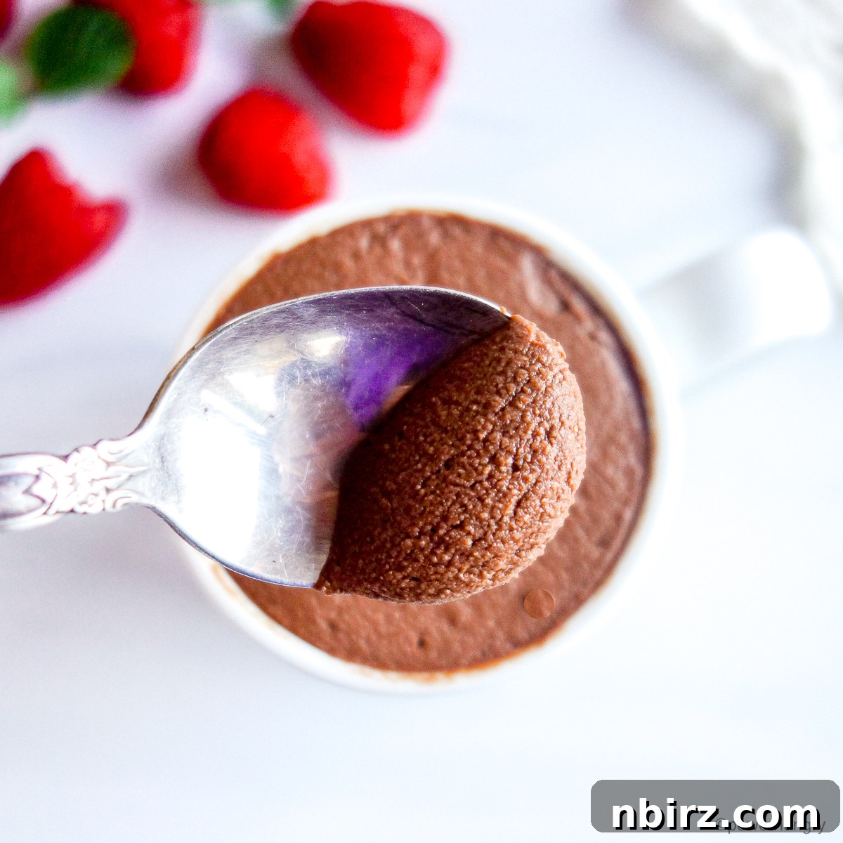 An overhead shot of vegan chocolate protein mousse served with a spoon, highlighting its smooth texture and inviting presentation.