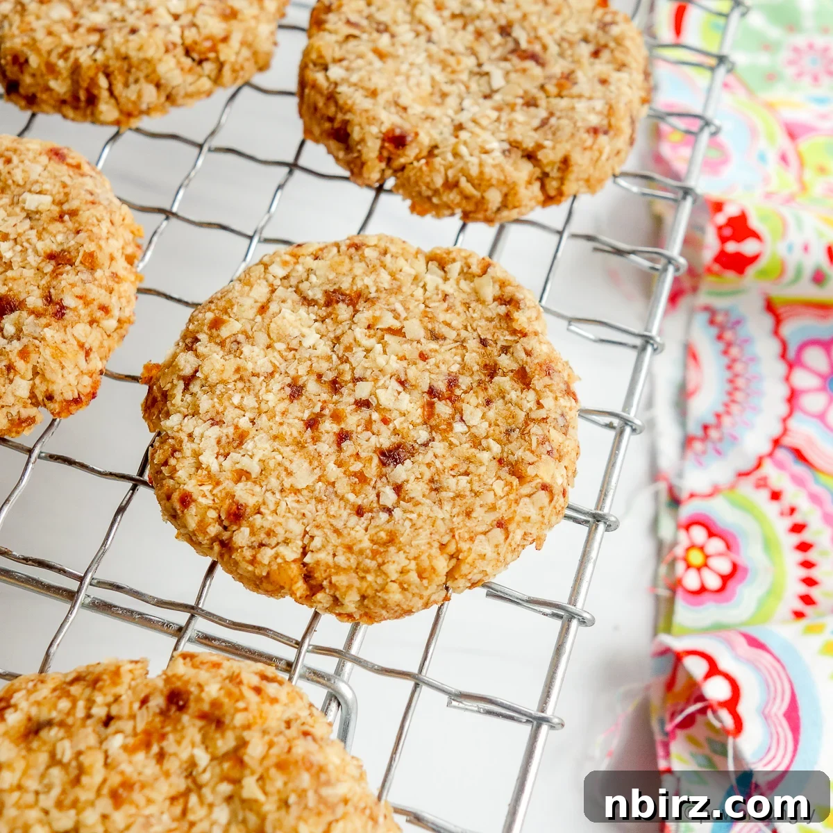 Wholesome Two-Ingredient Coconut Date Bites 3 Freshly baked coconut date cookies cooling on a wire rack.