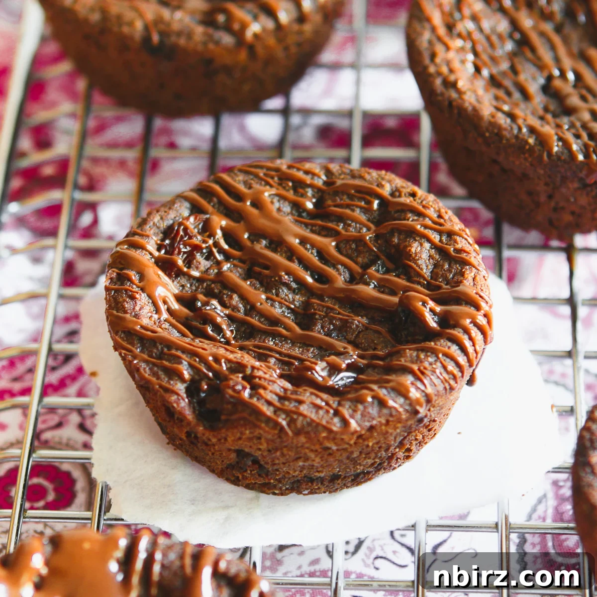 Epic Vegan Chocolate Cookies Grain and Oil Free 2 Two jumbo grain-free chocolate cookies cooling on a wire rack, sprinkled with mini chocolate chips.