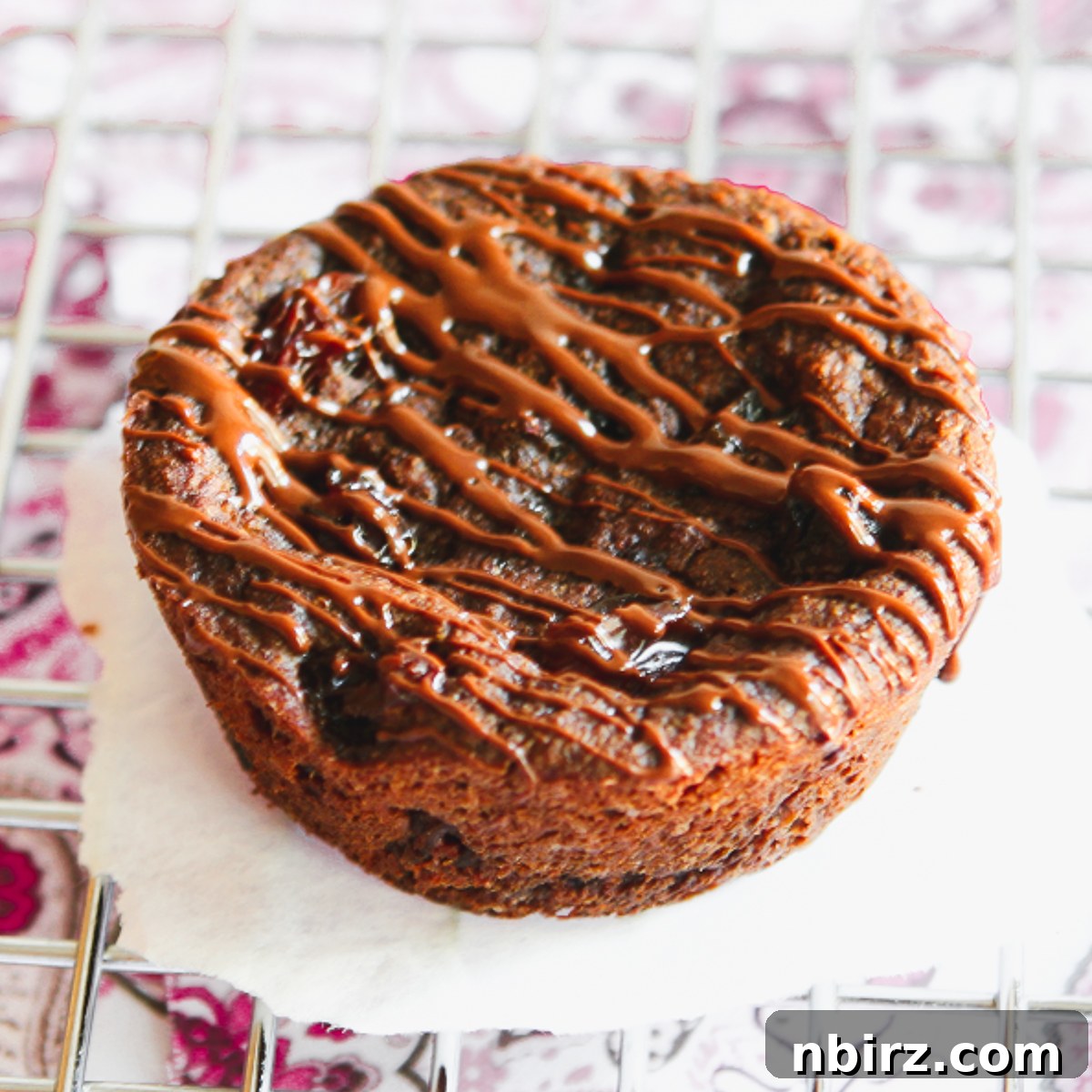 Epic Vegan Chocolate Cookies Grain and Oil Free 3 A single jumbo grain-free chocolate cookie sits on a wire cooling rack, showcasing its soft, textured surface.