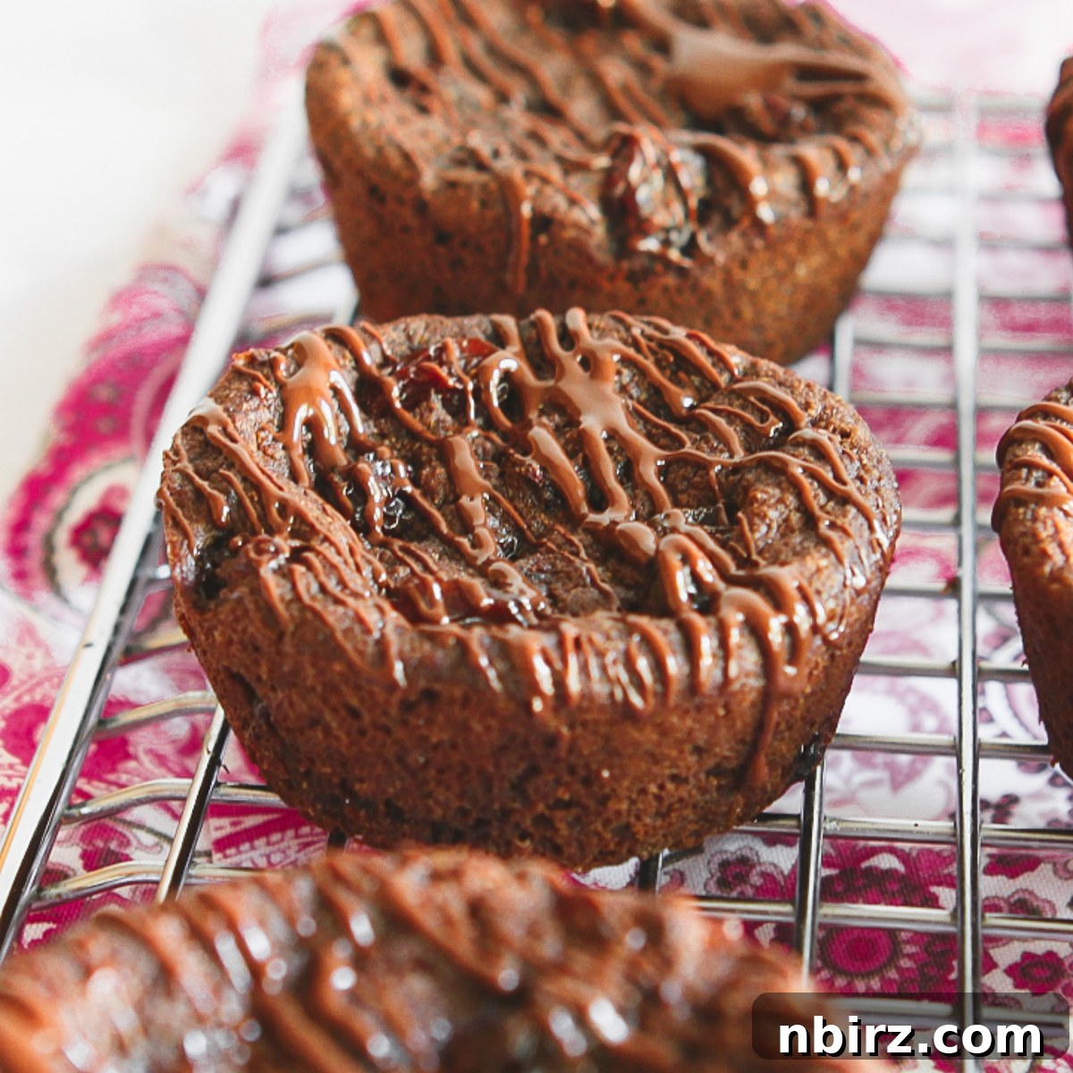 Epic Vegan Chocolate Cookies Grain and Oil Free 4 Three jumbo chocolate raisin cookies, still slightly warm, arranged on a cooling rack.