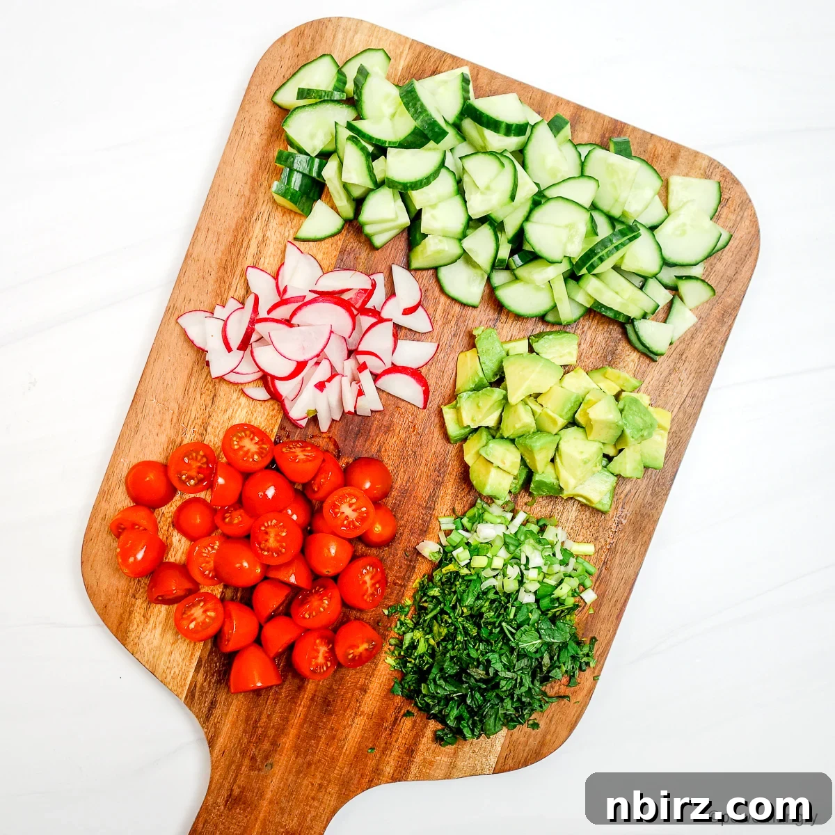 Protein Rich Oil Free Split Pea Salad 5 A colorful array of freshly chopped vegetables, including cucumber, radishes, and tomatoes, arranged on a wooden cutting board.