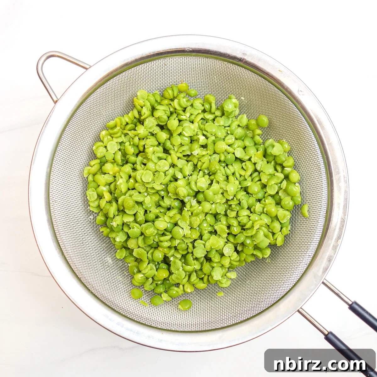 Protein Rich Oil Free Split Pea Salad 6 Cooked and drained split peas glistening in a silver mesh strainer under running cold water, cooling them down.