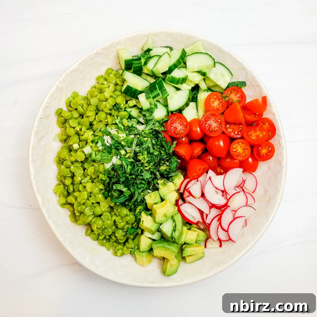 Protein Rich Oil Free Split Pea Salad 7 The bowl now contains cooked split peas combined with a colorful mix of chopped vegetables, awaiting the final toss.