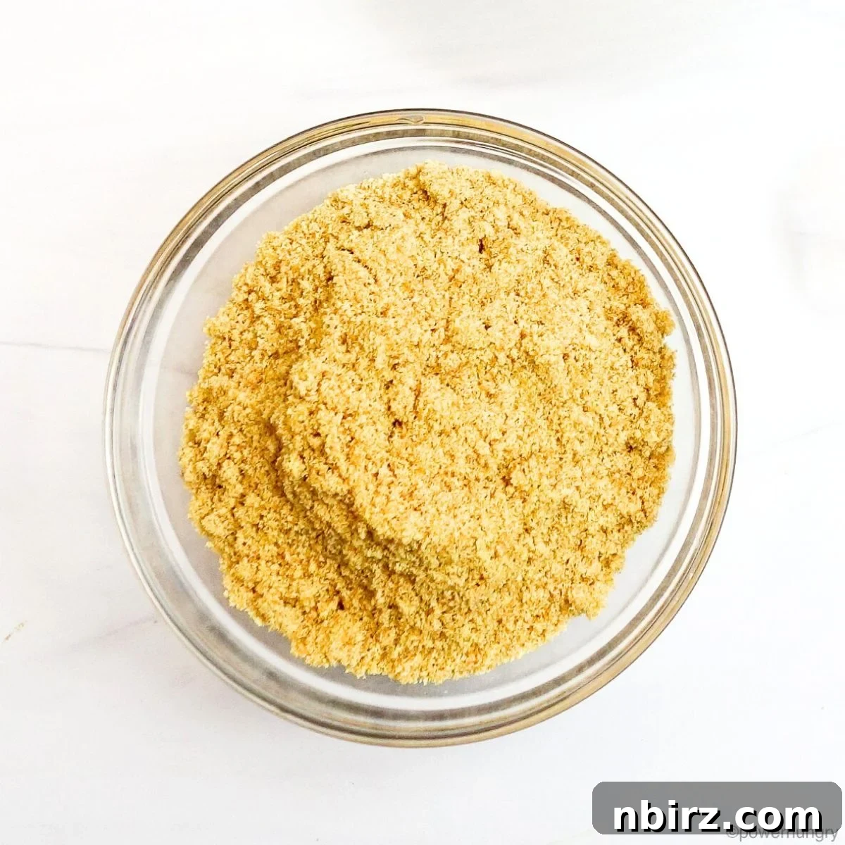 Golden flaxseed meal presented in a clear cup, highlighting its finely ground texture and nutritional readiness.