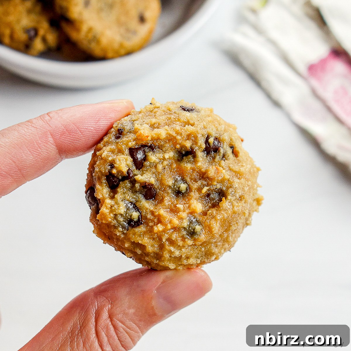 Deliciously Vegan Gluten-Free Almond Protein Cookies 11 A single perfectly baked almond flour protein cookie on a white surface.