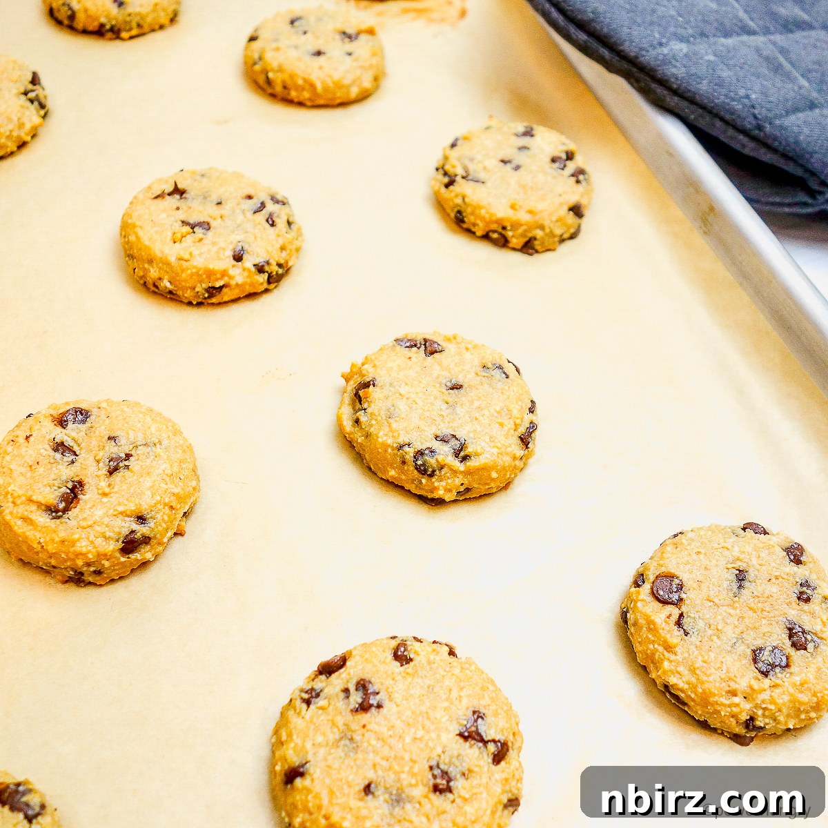 Deliciously Vegan Gluten-Free Almond Protein Cookies 9 Baked protein cookies on a parchment paper-lined baking sheet, fresh from the oven.