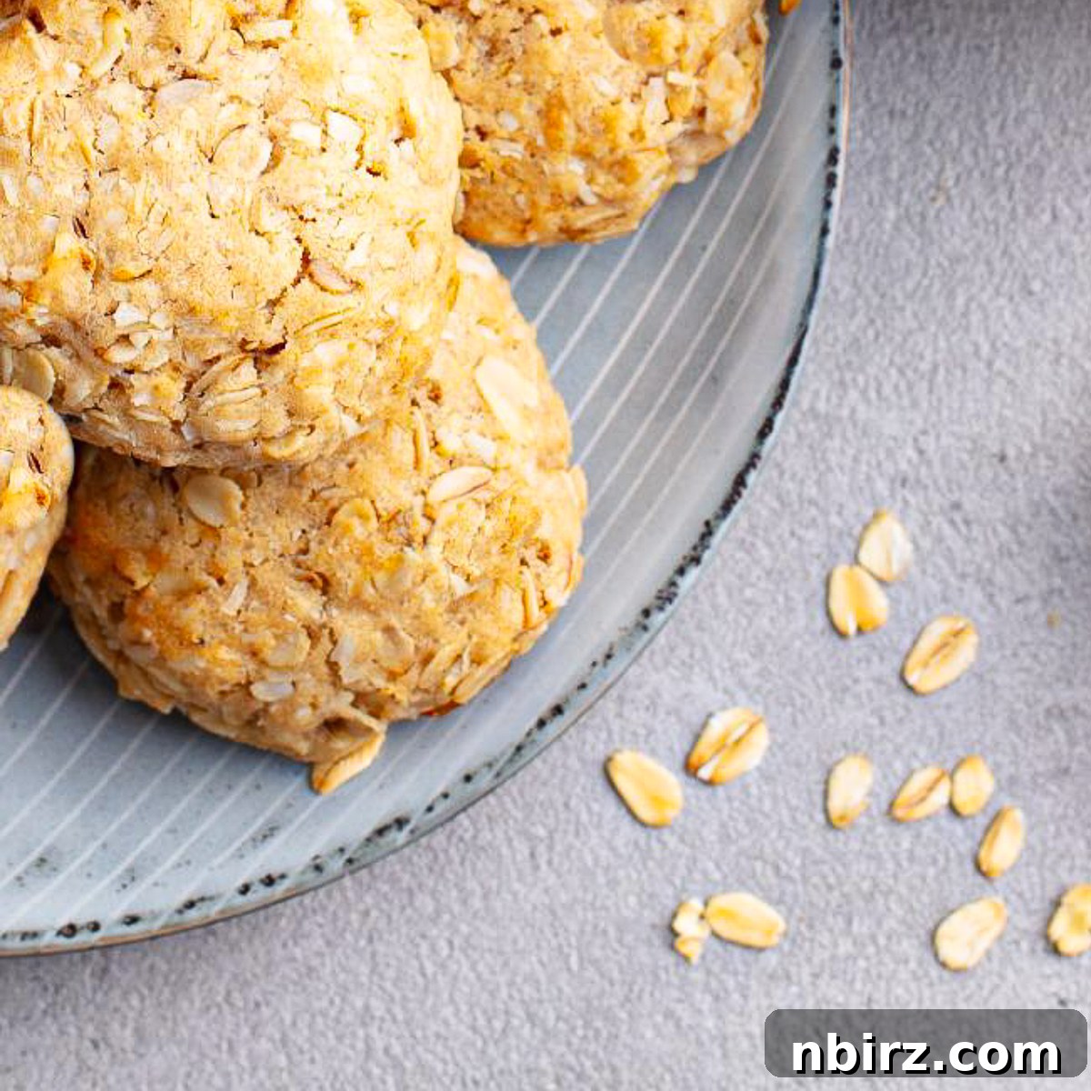 No-Fuss Almond Butter Oat Cookies 3 Almond oat flour cookies arranged on a plate with whole oats in a bowl next to them