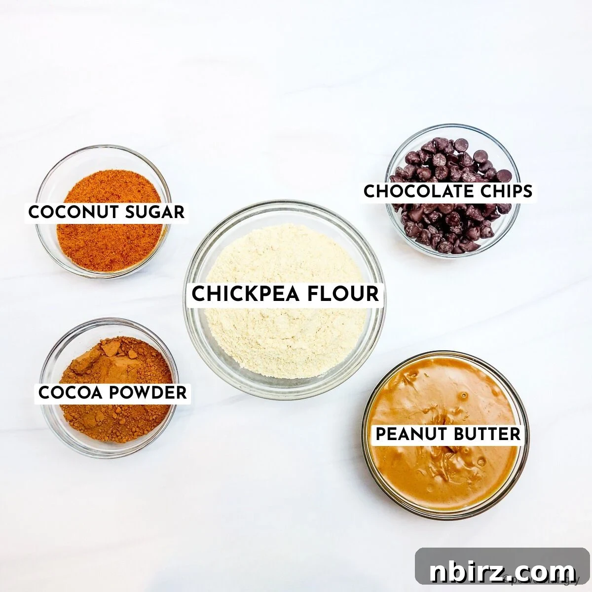 Decadent Vegan Gluten Free Chocolate Peanut Butter Chickpea Cookies 4 All five ingredients for chocolate peanut butter chickpea flour cookies arranged in glass bowls on a white surface