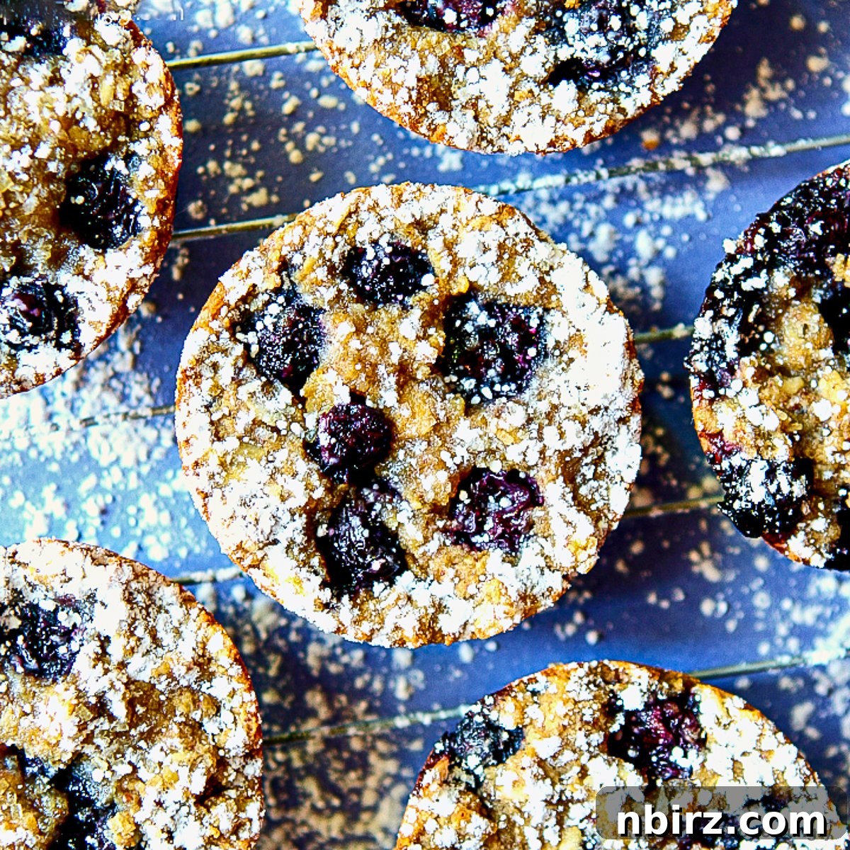 Freshly baked jumbo banana blueberry breakfast cookies in a muffin tin, showcasing crispy edges and golden brown tops.
