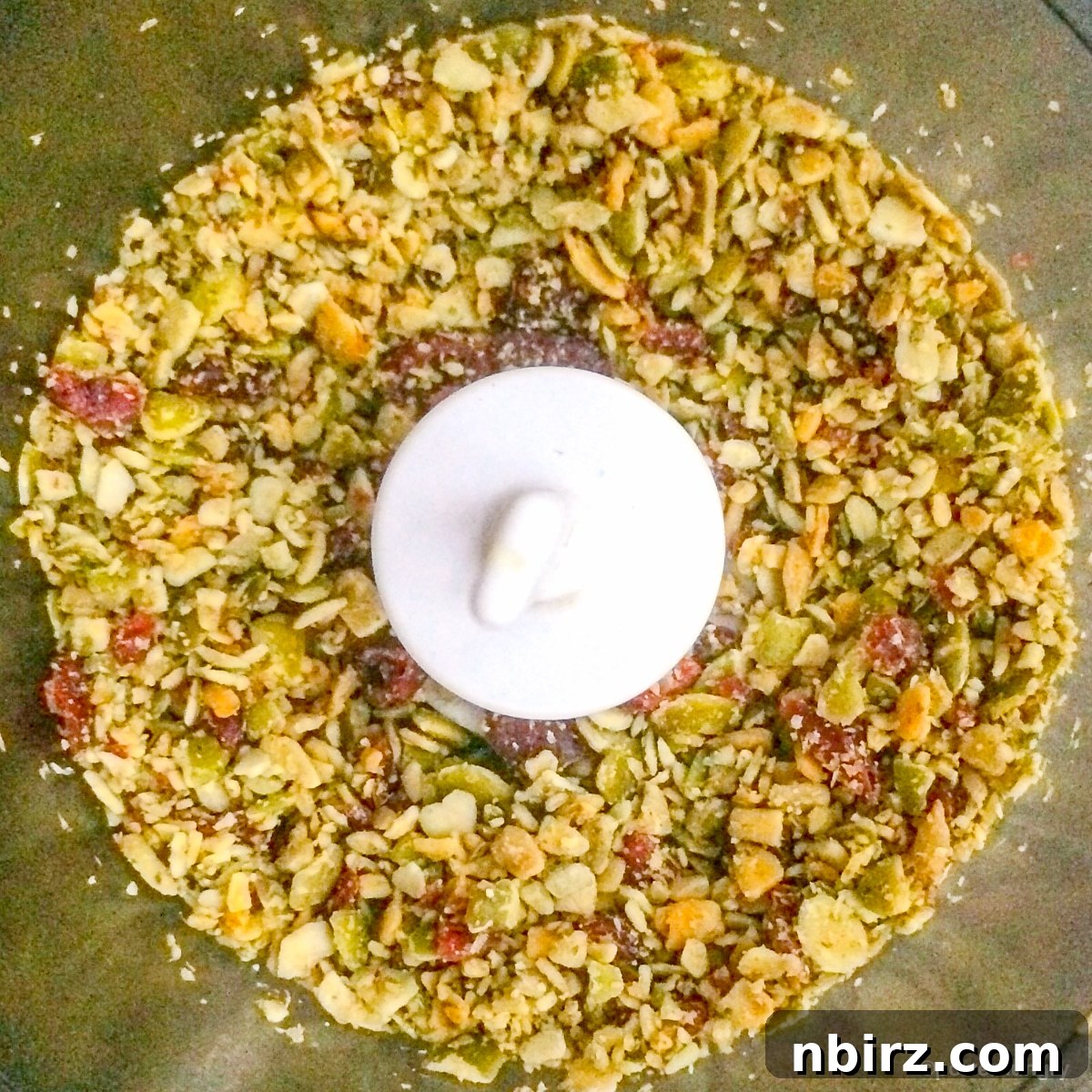 Close-up shot of chopped seeds and dried fruit in a food processor, ready to be mixed into the dough.