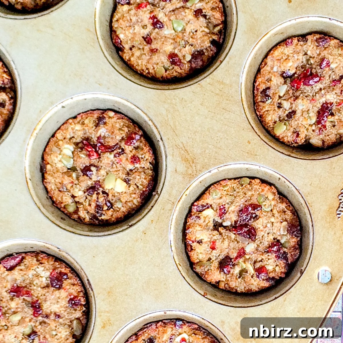 Overhead shot of granola protein cookies baking in a muffin tin, golden brown and perfectly formed.