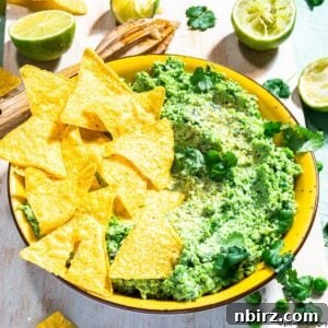 A vibrant bowl of green pea guacamole, perfect for serving with chips or vegetables.