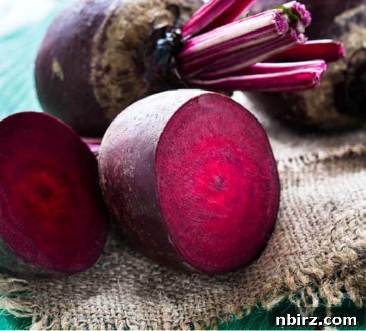 Fresh raw beets, one sliced in half to show its vibrant interior, resting on a rustic piece of burlap