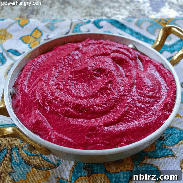 Close-up of vibrant 4-ingredient beet hummus in a decorative metal bowl, atop a colorful turquoise napkin
