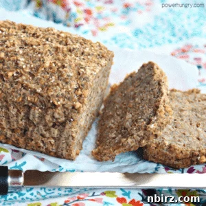 A loaf of buckwheat flax chia bread on a piece of white parchment paper atop a colorful floral napkin