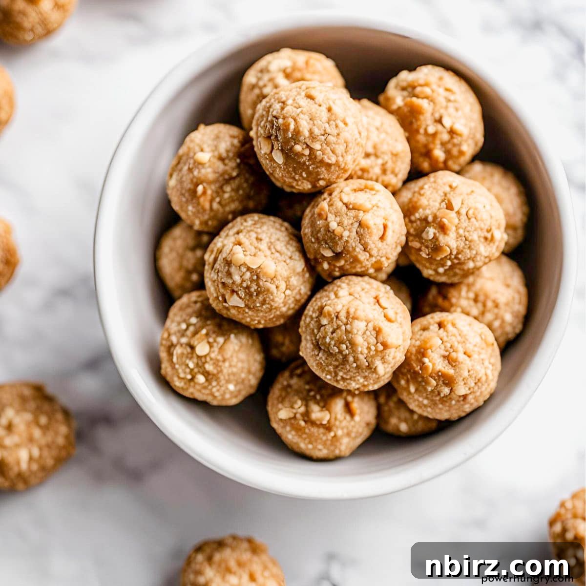 Wholesome Four-Ingredient Vegan No-Bake Cookie Dough Protein Bars 3 White bowl filled with delicious cookie dough protein balls, ready to be enjoyed as a healthy snack.