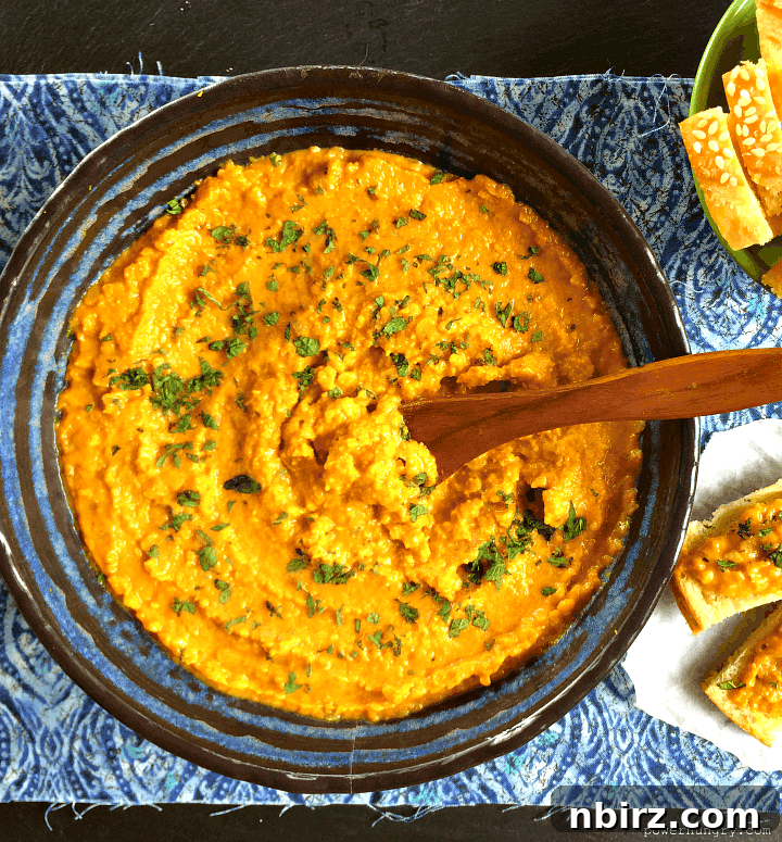 Creamy Vegan Red Lentil Protein Dip 4 Red lentil dal spread in a blue bowl with a wooden spoon