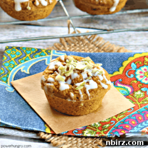 A charming vegan pumpkin latte mini muffin nestled on a piece of brown parchment paper, gracefully placed on a vibrant, colorful denim napkin, ready to delight.