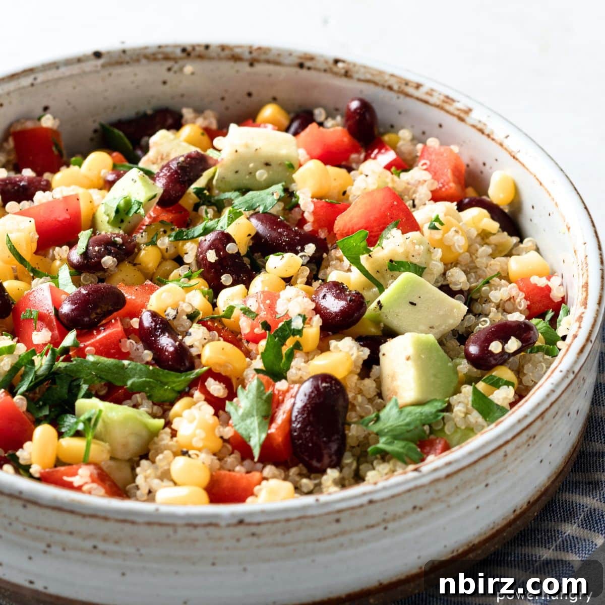 Close-up photo of Southwestern Quinoa Salad with vibrant ingredients including corn, beans, and bell peppers in a white bowl.