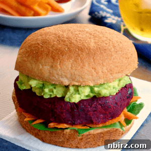Vegan beet burger on a bun with mashed avocado and vegetables