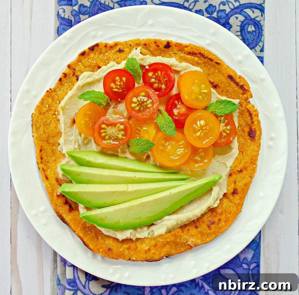 Effortless 3 Ingredient Gluten Free Sweet Potato Tortillas 3 Overhead shot of a single sweet potato tortilla generously topped with fresh vegetables and avocado slices, showcasing its versatility.
