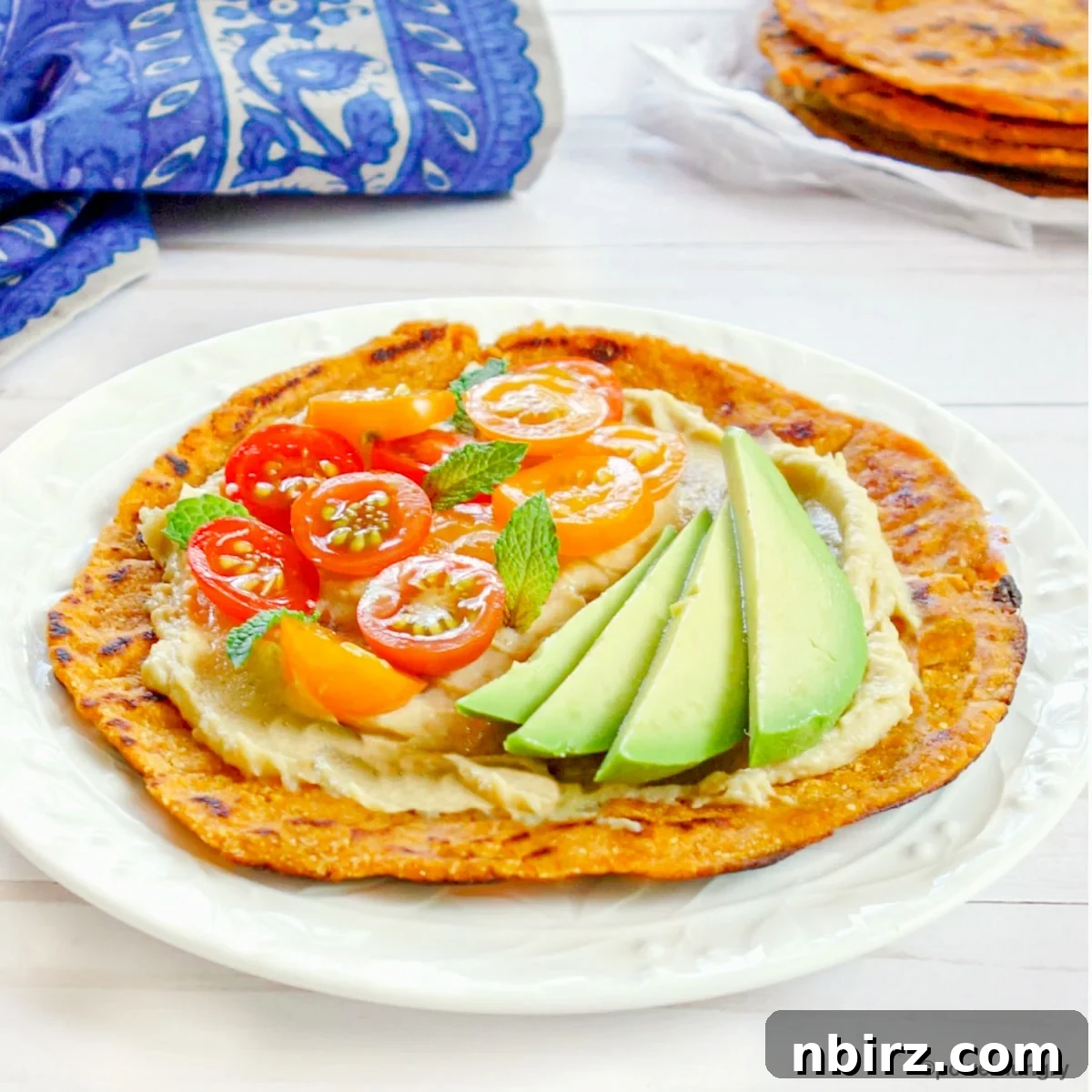 Effortless 3 Ingredient Gluten Free Sweet Potato Tortillas 9 A single sweet potato tortilla generously topped with a colorful array of fresh vegetables and herbs, ready to eat.