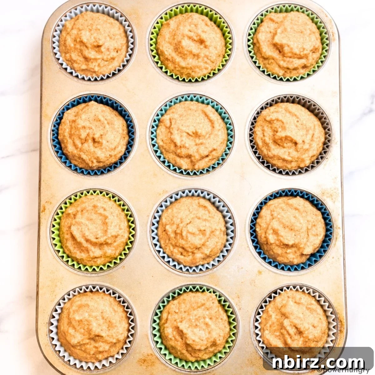 Portions of muffin batter scooped into muffin cups