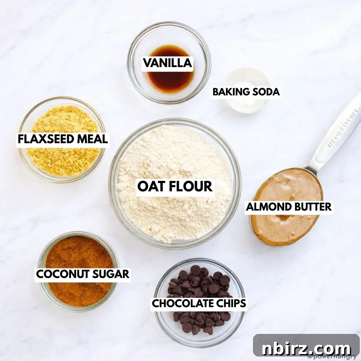 A selection of raw ingredients for oat flour chocolate chip cookies, including oat flour, almond butter, chocolate chips, and coconut sugar.