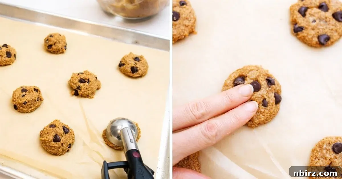 Portioning chocolate chip cookie dough onto a parchment-lined baking sheet, showing flattened cookie shapes.