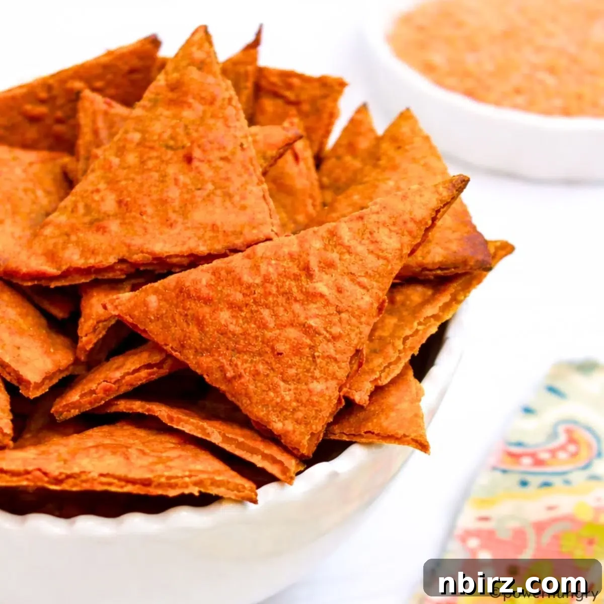 Crunchy Zesty High Protein Lentil Chips Vegan Grain Free 10 A bowl overflowing with crispy, high-protein red lentil chips, perfect for a healthy snack.
