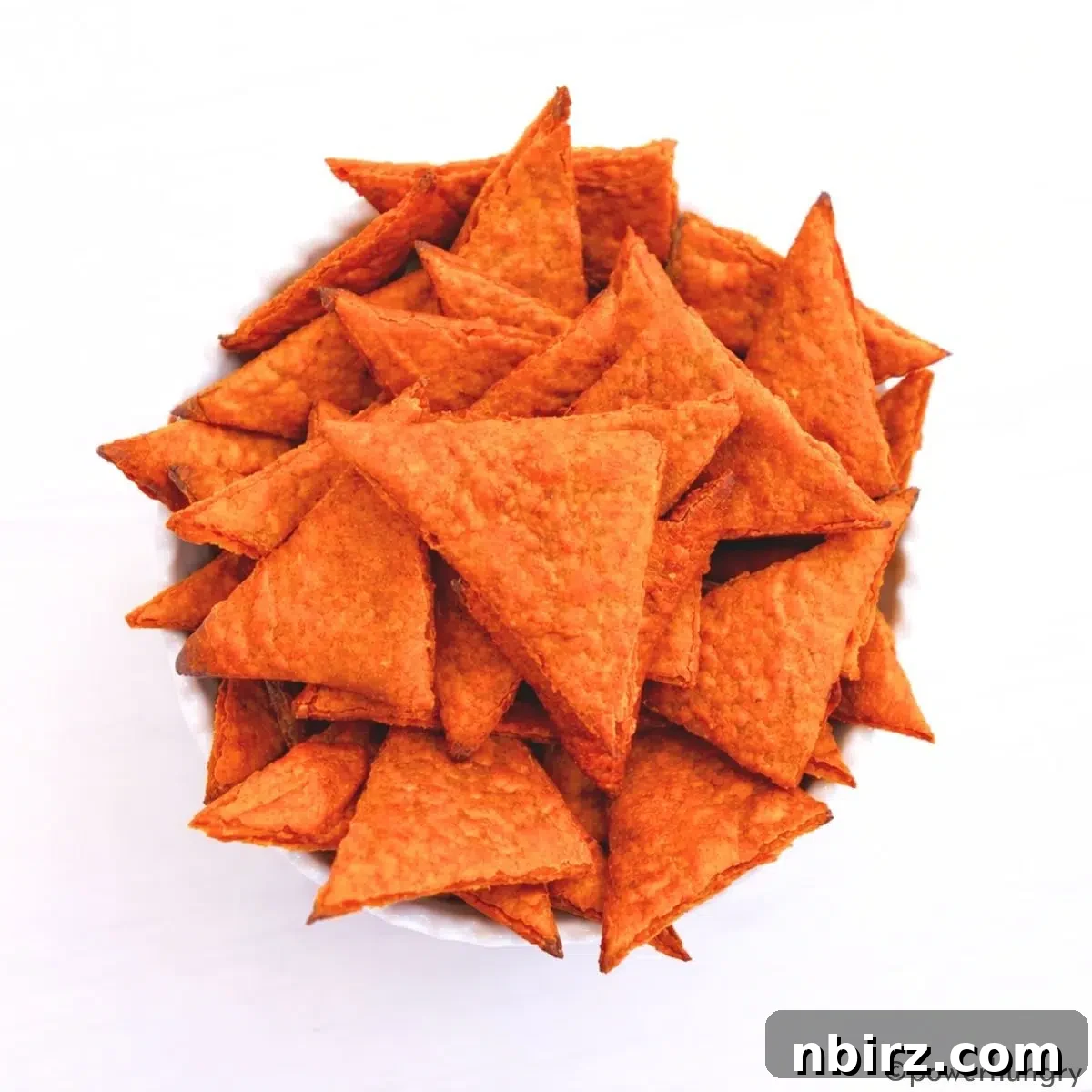 Crunchy Zesty High Protein Lentil Chips Vegan Grain Free 3 A beautiful white ceramic bowl filled to the brim with golden-orange, high-protein lentil chips, ready for snacking.