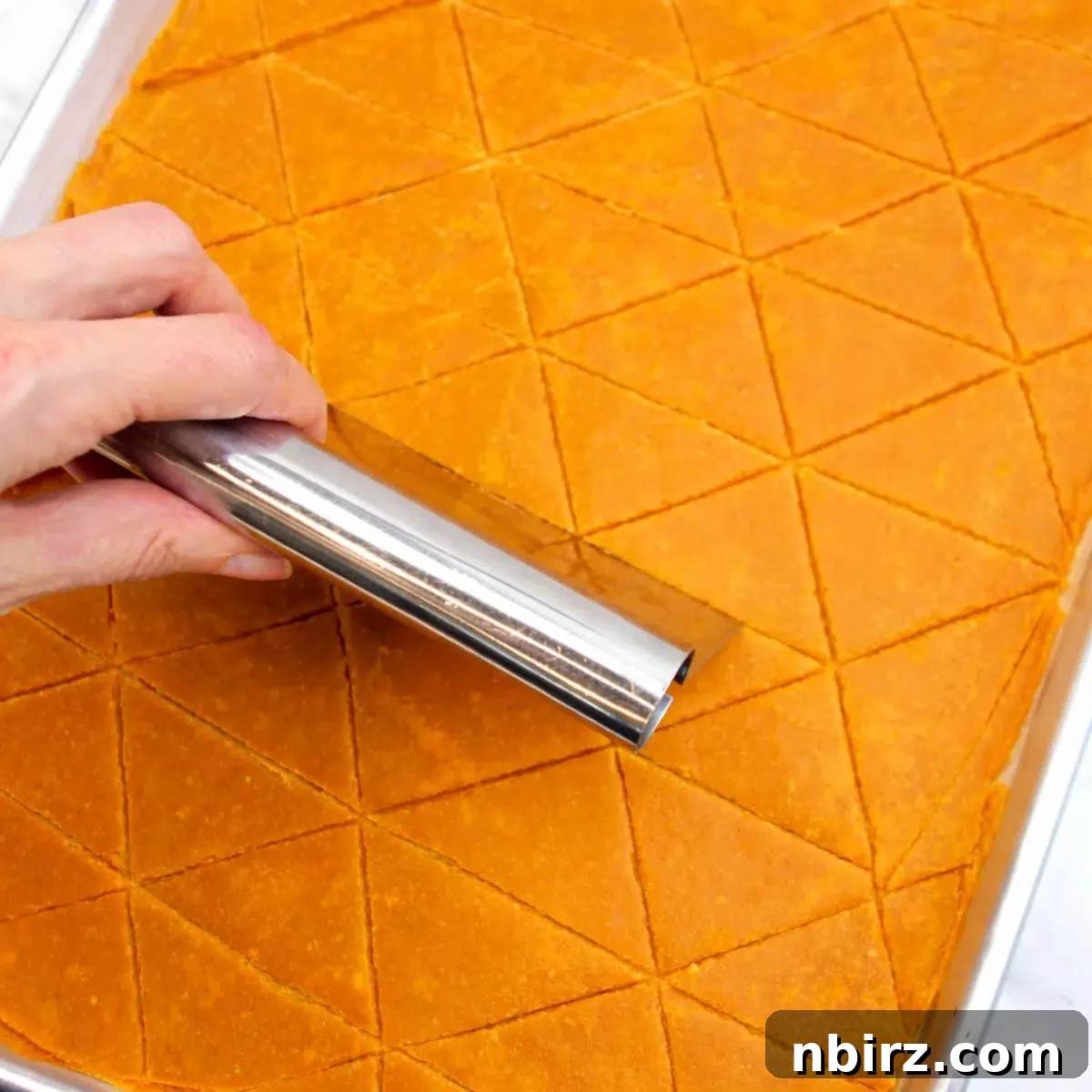 Crunchy Zesty High Protein Lentil Chips Vegan Grain Free 7 Baked lentil batter being cut into triangle shapes with a pizza cutter on a baking sheet.