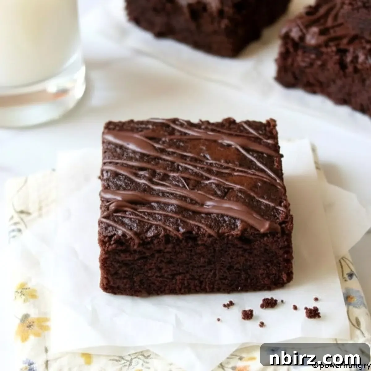 Decadent Grain-Free Vegan Carob Almond Brownies 2 Fudgy vegan carob almond flour brownie on a napkin with a glass of plant-based milk, highlighting its rich texture.