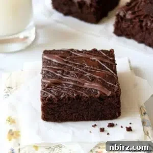 Fudgy vegan carob almond flour brownie on a napkin with a glass of plant-based milk.